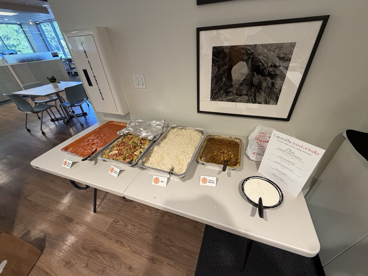 Buffet trays of butter chicken, chana masala and basmati rice with Jewel of India dish labels, set up for an office lunch in Seattle